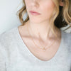 Woman wearing Salt white druzy stone gold necklace and gold Twinkle necklace layered
