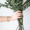 Woman wearing gold bracelets and holding bouquet
