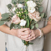 Woman wearing Priority rings and bracelets holding a bouquet of flowers