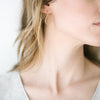 Woman wearing Storm gold earrings