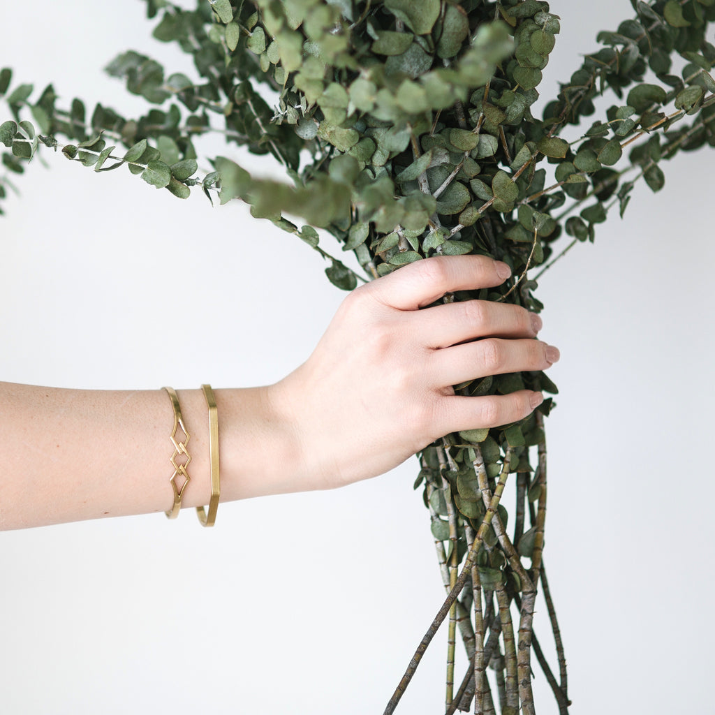 Woman wearing gold cuff bracelets holding bouquet of flowers