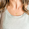 Woman wearing gold rainbow stamped necklace