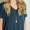 Woman wearing layered Plume gold feather necklaces