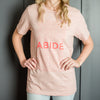 Woman wearing pink abide shirt and jeans