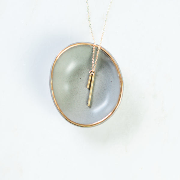 Stability gold bar necklace on ring dish