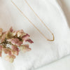 Gold Gospel necklace on white cloth with flowers