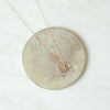 Trio rose gold ring necklace on coaster