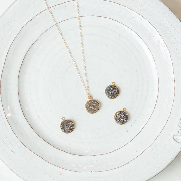 Laden druzy stone gold necklace on plate with loose druzy stone pendants