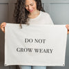 Woman holding Do Not Grow Weary endurance flag