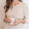 Woman wearing assist necklace and holding mug