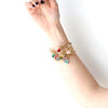 Woman wearing gold bracelet with glass stone charms