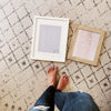 Woman standing by grey and pink framed art prints on a rug