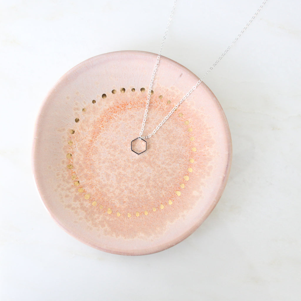 Small silver hexagon necklace on plate